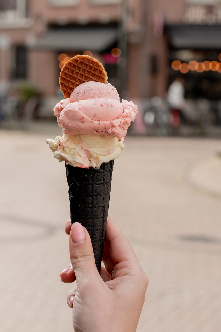 Roze ijs in een zwart hoorntje